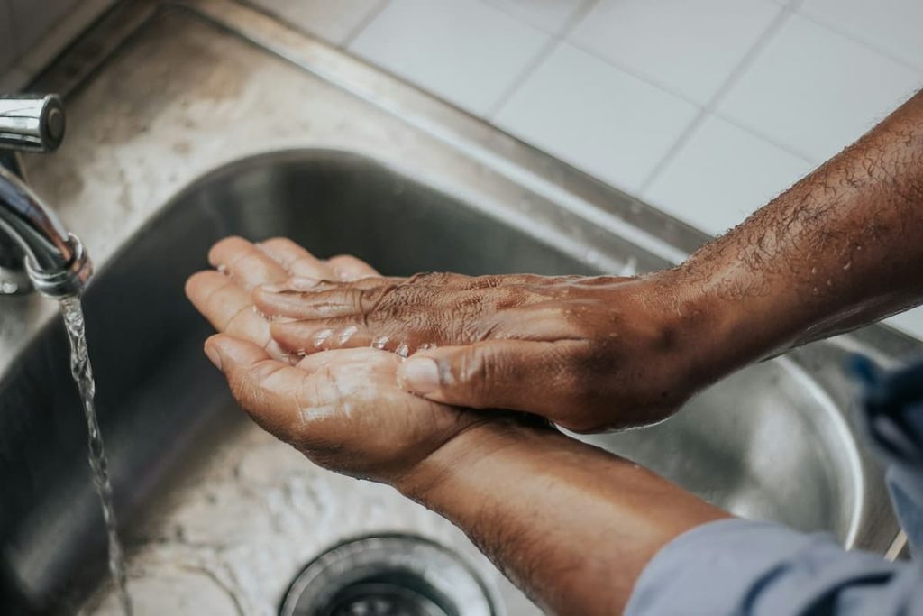 A person washing their hands at a bathroom sink.